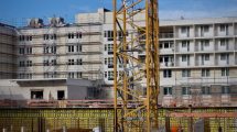 Canteiro de obras com um guindaste ao lado de um edifício em construção sob céu claro.