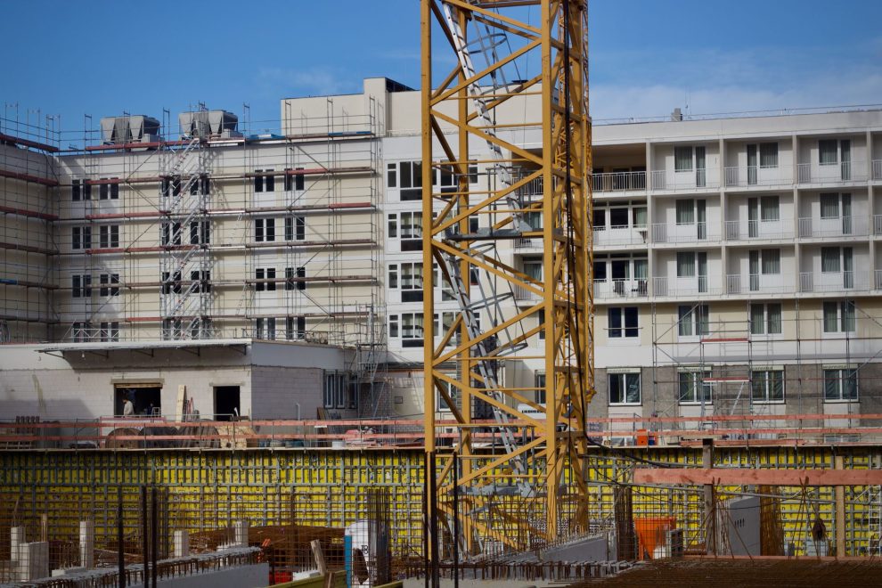 Canteiro de obras com um guindaste ao lado de um edifício em construção sob céu claro.