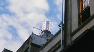 Caixa-d’água instalada no topo de uma edificação contra um céu azul com nuvens.