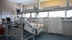 Leito de unidade de terapia intensiva cercado por equipamentos médicos modernos em um ambiente hospitalar.
