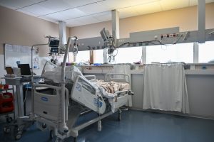 Leito de unidade de terapia intensiva cercado por equipamentos médicos modernos em um ambiente hospitalar.