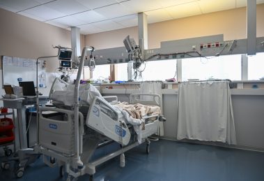 Leito de unidade de terapia intensiva cercado por equipamentos médicos modernos em um ambiente hospitalar.