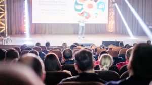 Público acompanha uma apresentação em um auditório durante uma conferência.
