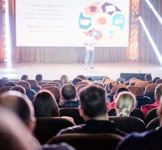 Público acompanha uma apresentação em um auditório durante uma conferência.