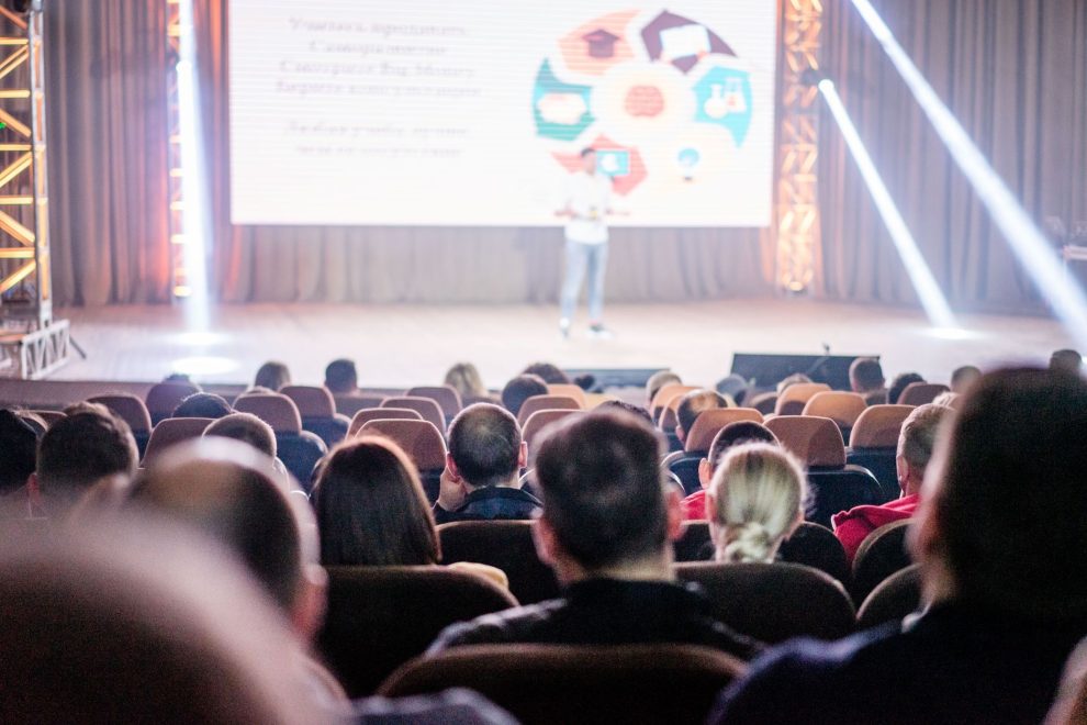 Público acompanha uma apresentação em um auditório durante uma conferência.