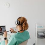 Profissional de saúde realiza uma consulta médica por videochamada em um escritório.