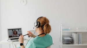 Profissional de saúde realiza uma consulta médica por videochamada em um escritório.