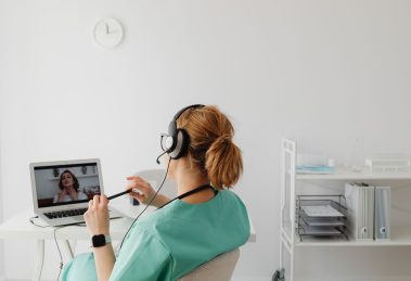 Profissional de saúde realiza uma consulta médica por videochamada em um escritório.