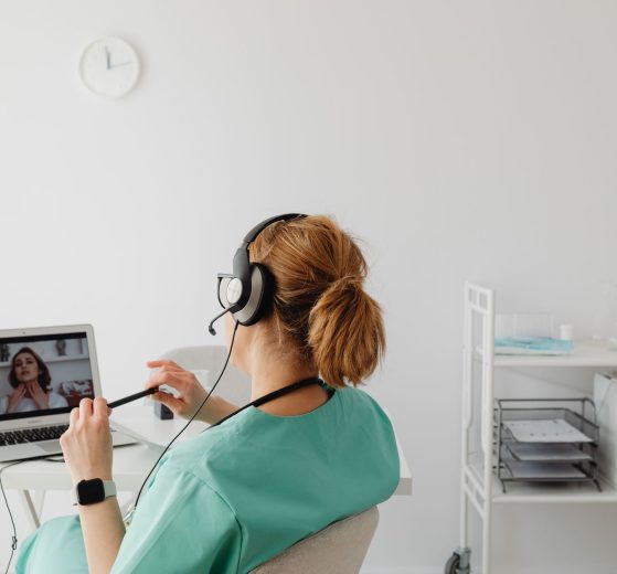 Profissional de saúde realiza uma consulta médica por videochamada em um escritório.