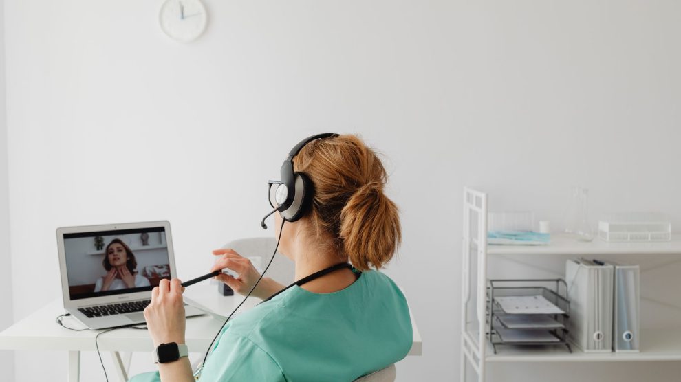 Profissional de saúde realiza uma consulta médica por videochamada em um escritório.