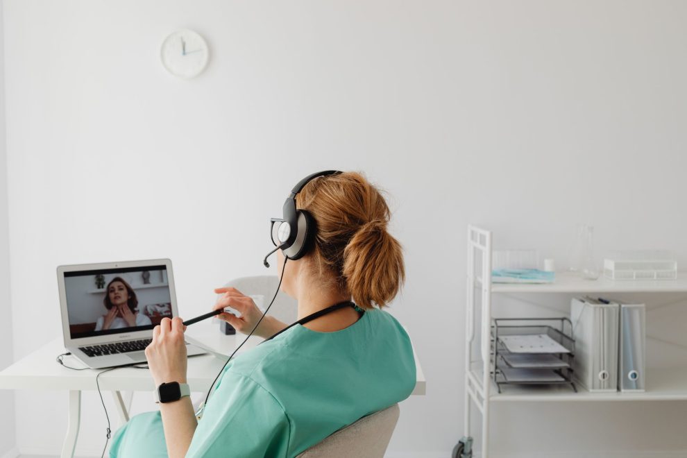 Profissional de saúde realiza uma consulta médica por videochamada em um escritório.