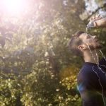 Homem despeja água sobre a cabeça para se refrescar em um dia ensolarado.