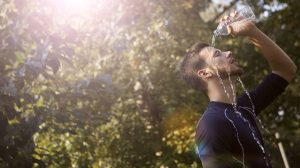 Homem despeja água sobre a cabeça para se refrescar em um dia ensolarado.
