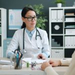 Médico conversa com paciente durante consulta em uma clínica.