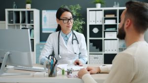 Médico conversa com paciente durante consulta em uma clínica.