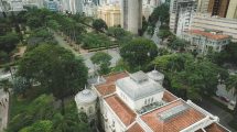 Vista aérea da Praça da Liberdade, em Belo Horizonte, cercada por edifícios de arquitetura neoclássica e áreas verdes.