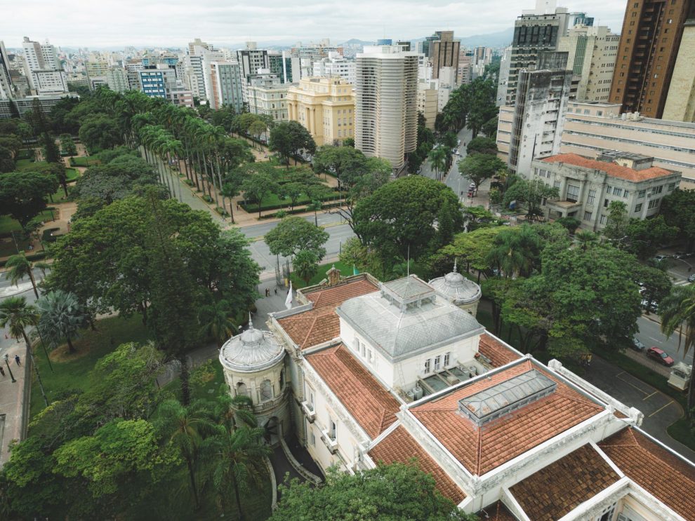 Vista aérea da Praça da Liberdade, em Belo Horizonte, cercada por edifícios de arquitetura neoclássica e áreas verdes.