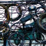 Emaranhado de cabos de energia e telecomunicações instalado ao ar livre.