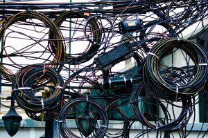 Emaranhado de cabos de energia e telecomunicações instalado ao ar livre.
