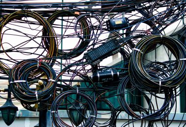 Emaranhado de cabos de energia e telecomunicações instalado ao ar livre.