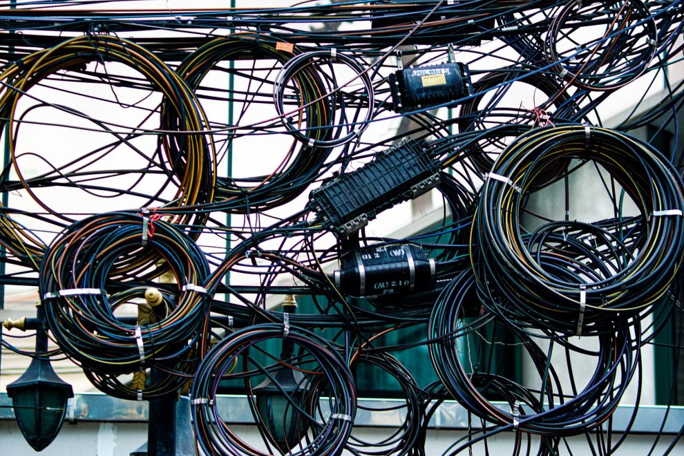 Emaranhado de cabos de energia e telecomunicações instalado ao ar livre.