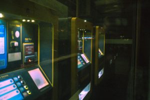 Fileira de terminais de autoatendimento iluminados em um ambiente escuro.