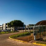 Vista de um campus universitário em Apucarana, no Paraná, com edifícios e áreas arborizadas sob céu azul.