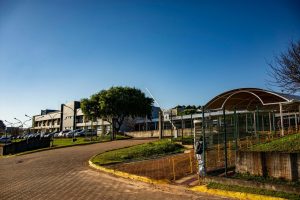 Vista de um campus universitário em Apucarana, no Paraná, com edifícios e áreas arborizadas sob céu azul.