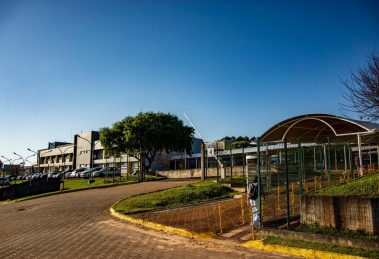 Vista de um campus universitário em Apucarana, no Paraná, com edifícios e áreas arborizadas sob céu azul.