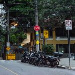 Motocicletas estacionadas em uma rua de Belo Horizonte, diante de placas e sinalização urbana.