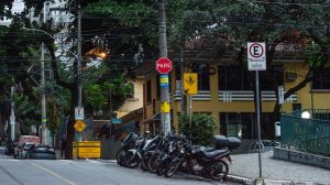 Motocicletas estacionadas em uma rua de Belo Horizonte, diante de placas e sinalização urbana.