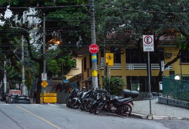 Motocicletas estacionadas em uma rua de Belo Horizonte, diante de placas e sinalização urbana.