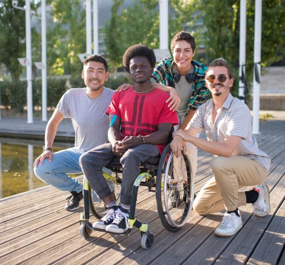 Grupo diverso de amigos em um parque, incluindo uma pessoa em cadeira de rodas, reunido em um momento de convivência ao ar livre.