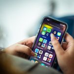 Mulher segura um smartphone que exibe diversos aplicativos.