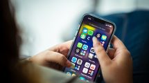 Mulher segura um smartphone que exibe diversos aplicativos.