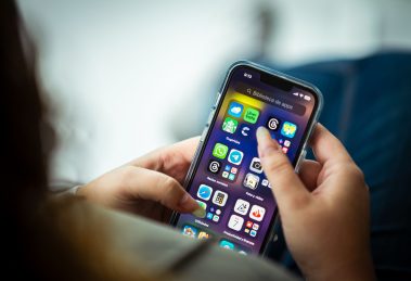 Mulher segura um smartphone que exibe diversos aplicativos.