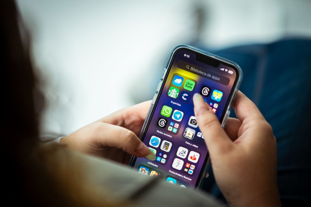 Mulher segura um smartphone que exibe diversos aplicativos.