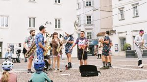Banda toca instrumentos ao ar livre enquanto anima o público em um espaço público.