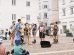 Banda toca instrumentos ao ar livre enquanto anima o público em um espaço público.